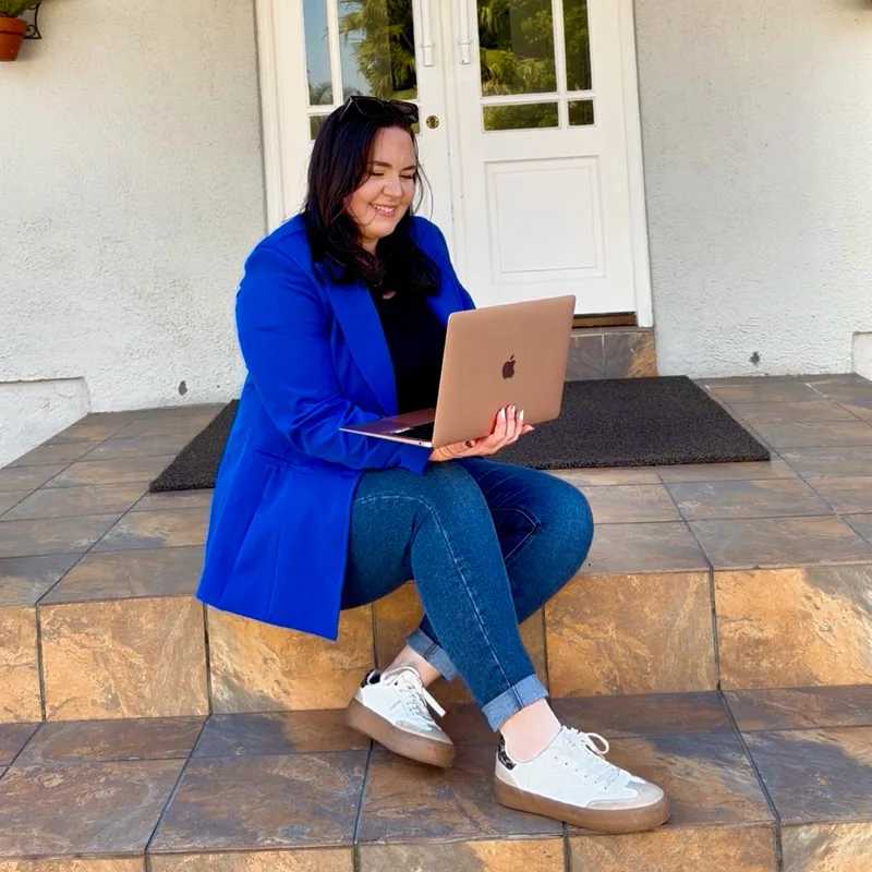 Georgia May sitting on a doorstep with a laptop open on her knees.